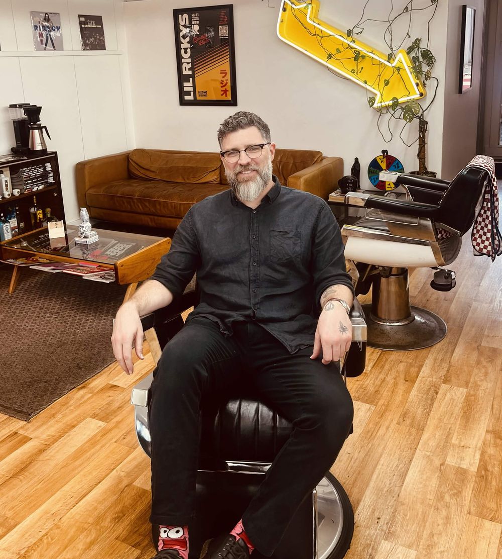 Rob Lee, barber, sitting in a vintage barber chair at Lil' Ricky's in North Perth